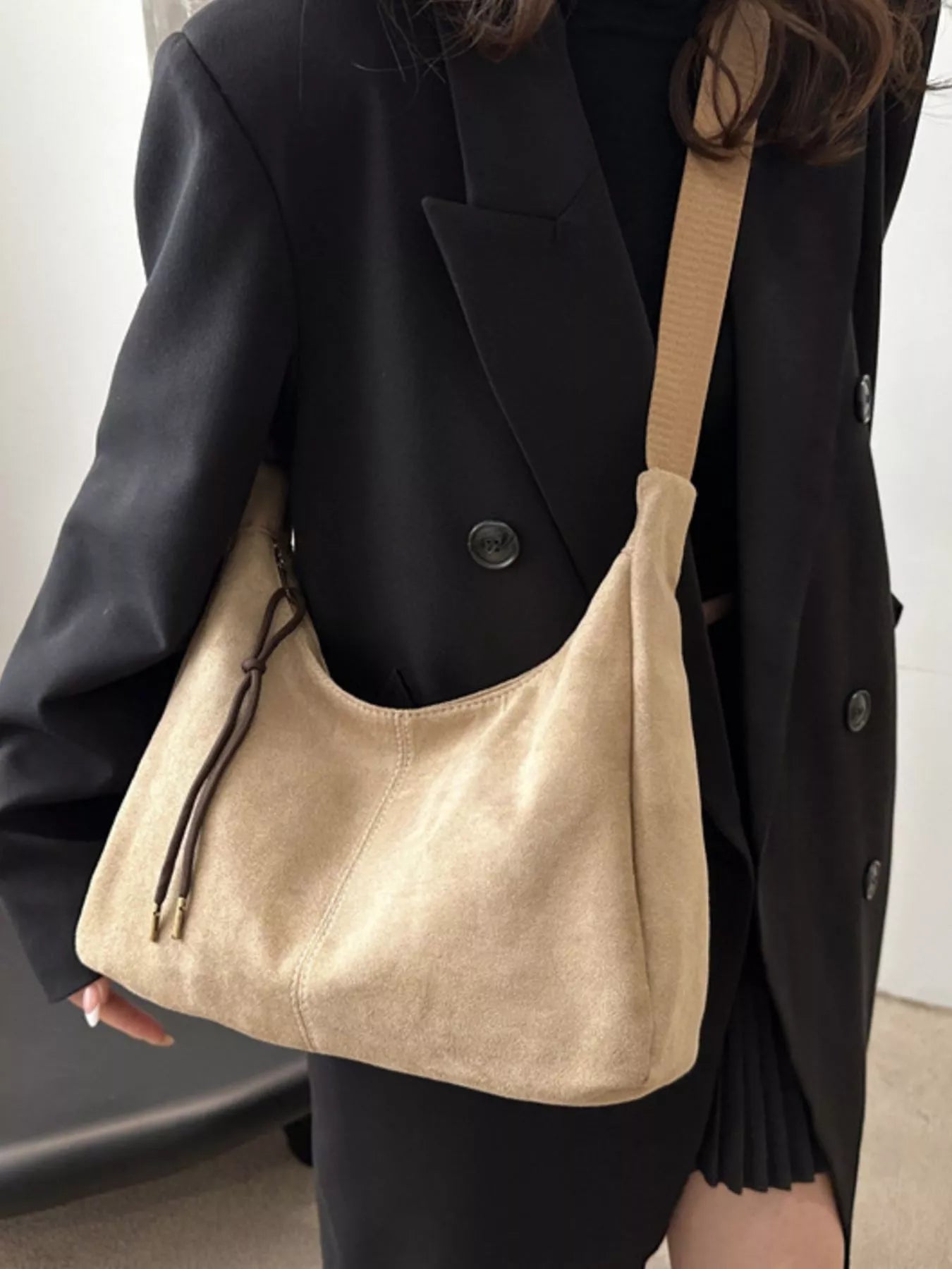 Person holding a beige handbag with a plain background