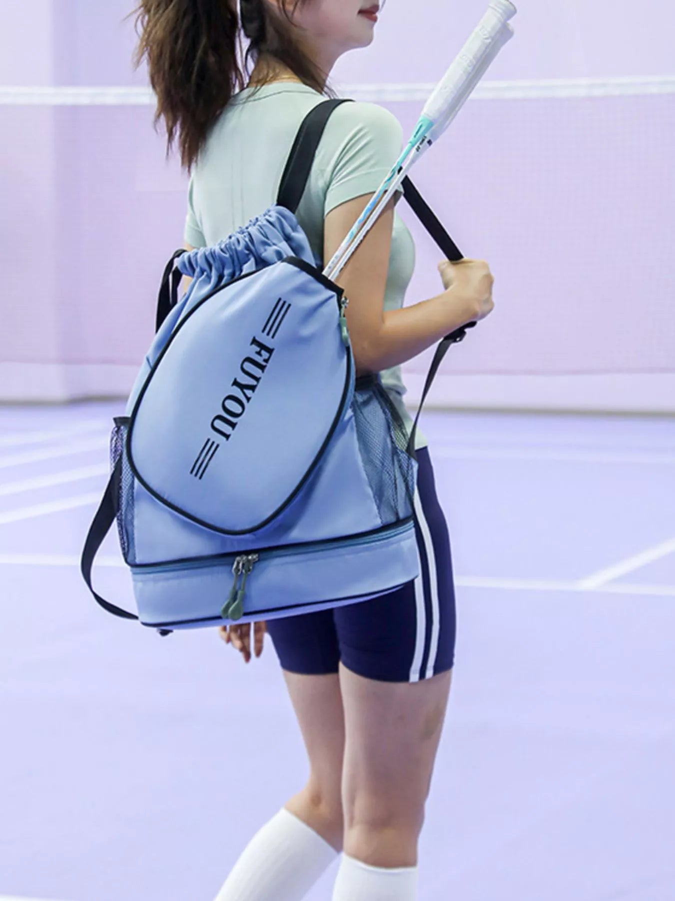 Person holding a blue sports bag with 'Pony' branding on a tennis court.