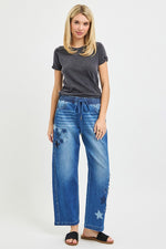 Woman wearing a gray t-shirt and blue jeans with star patterns on a white background