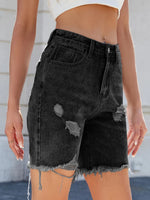 Black distressed denim shorts worn by a person with a neutral background