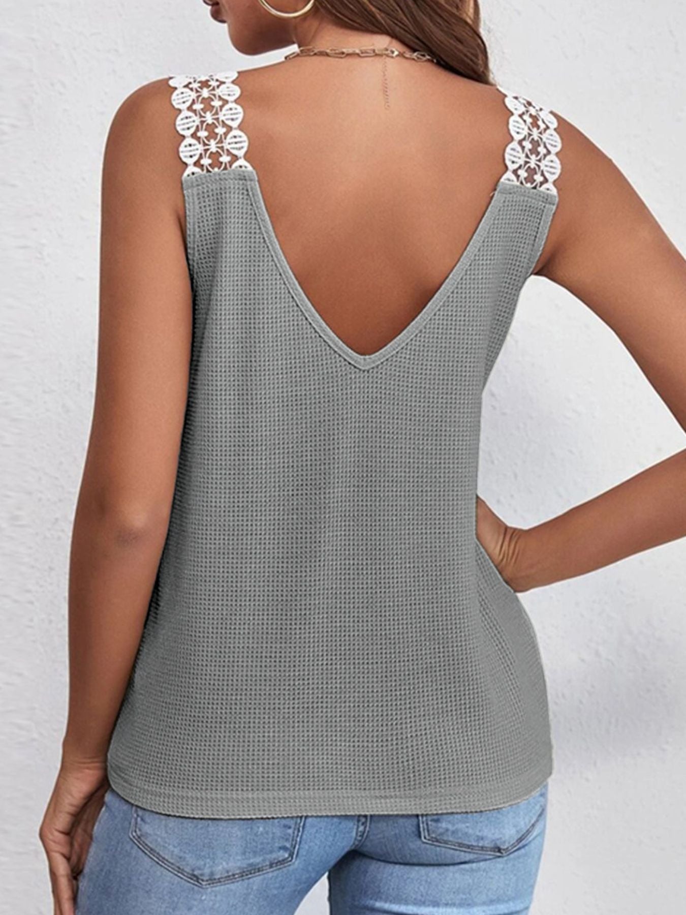 Gray tank top with lace straps worn by a person on a white background