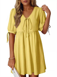 Yellow dress with short sleeves and a tie waist worn by a person on a white background