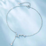Silver constellation necklace on a light blue fabric background