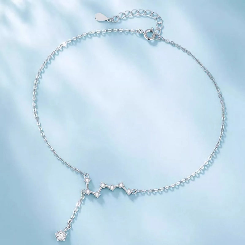 Silver constellation necklace on a light blue fabric background
