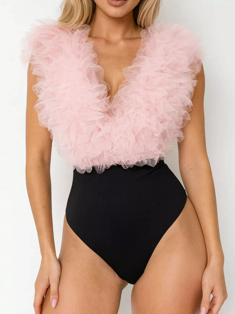 Woman wearing a black swimsuit with a pink ruffled top against a white background