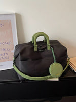 Black duffel bag with green handles and strap on a surface