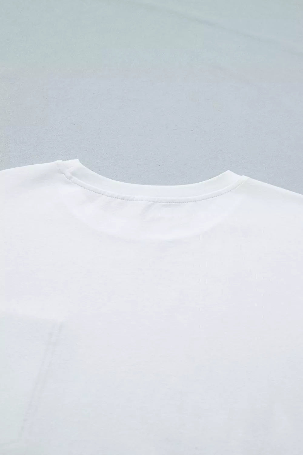 Close-up of a white t-shirt on a light gray background