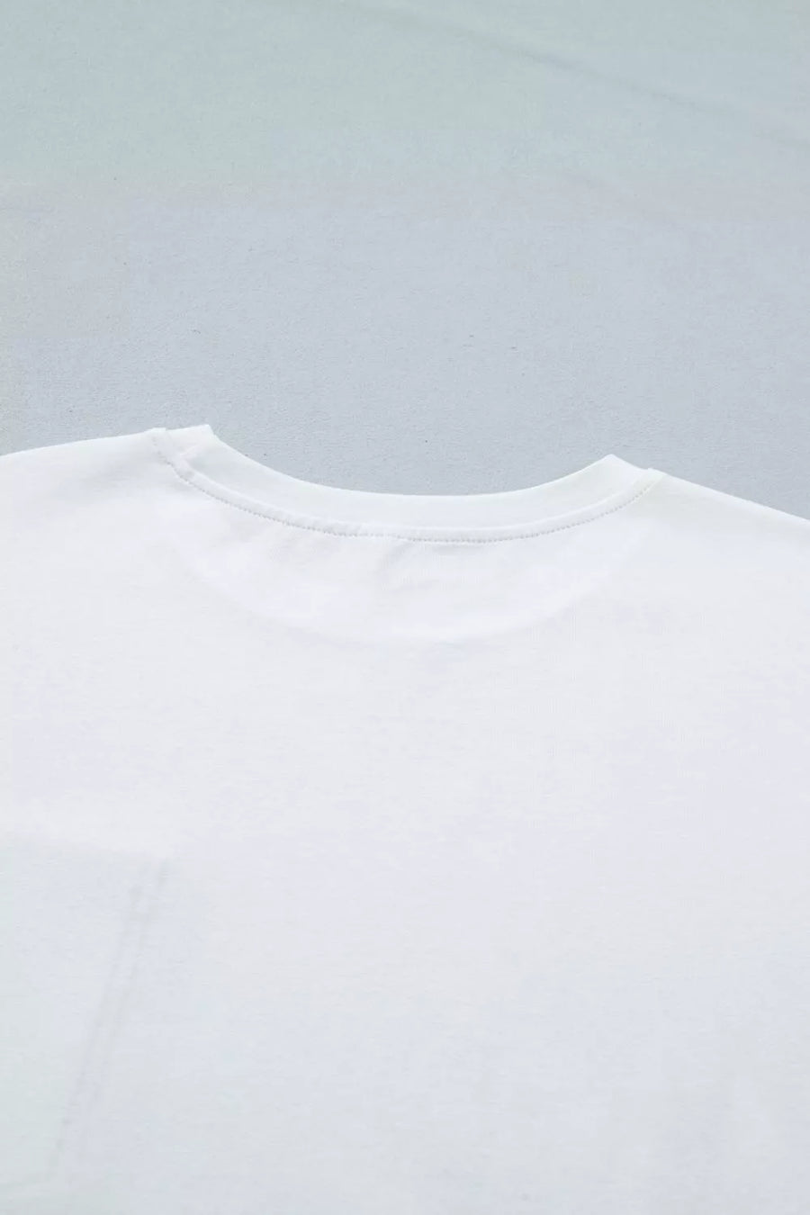Close-up of a white t-shirt on a light gray background