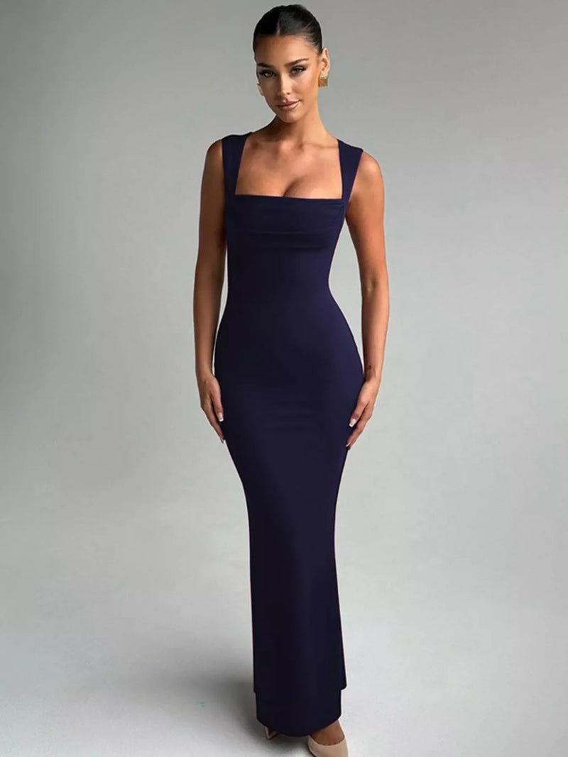 Woman wearing a dark blue evening gown against a gray background