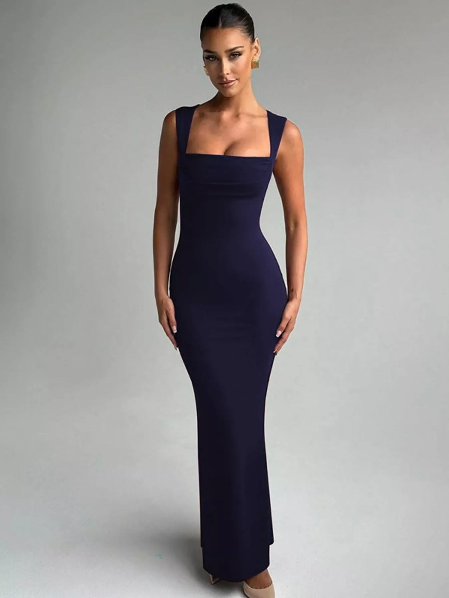 Woman wearing a dark blue evening gown against a gray background