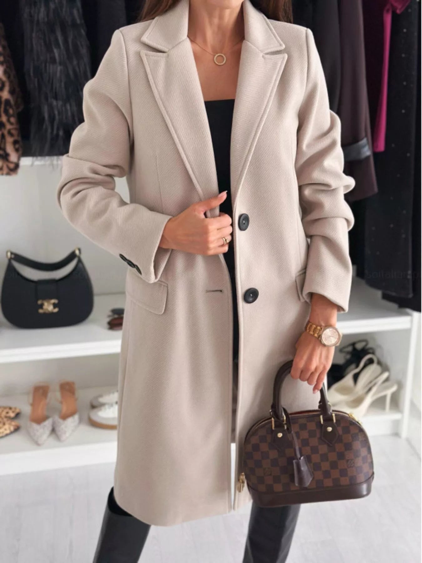 Person wearing a beige coat holding a brown handbag in a clothing store setting