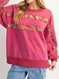 Pink sweatshirt with floral patterns on a plain background