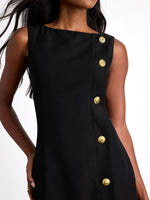 Black dress with gold buttons worn by a model on a white background