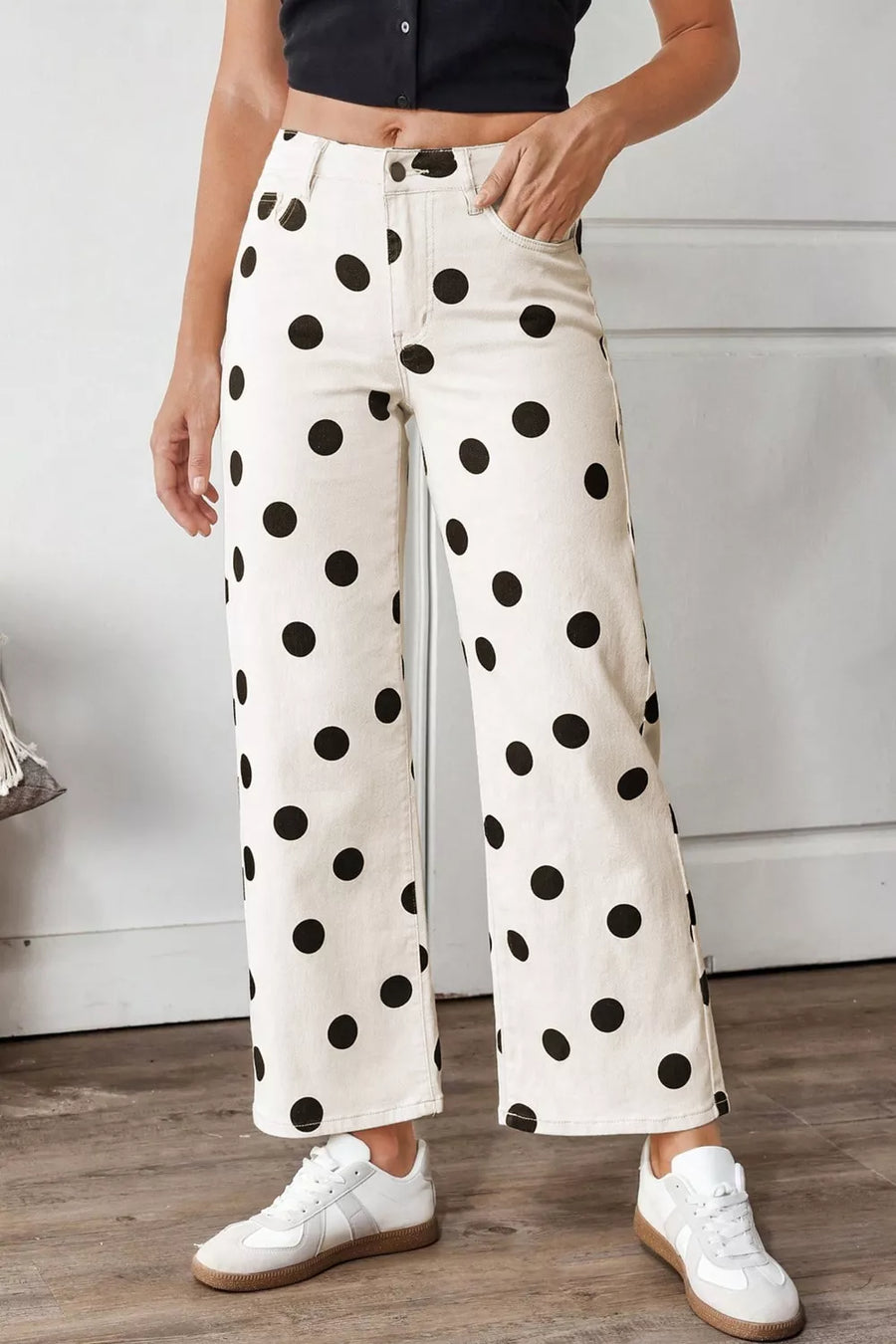 Person wearing white pants with black polka dots and white sneakers indoors.