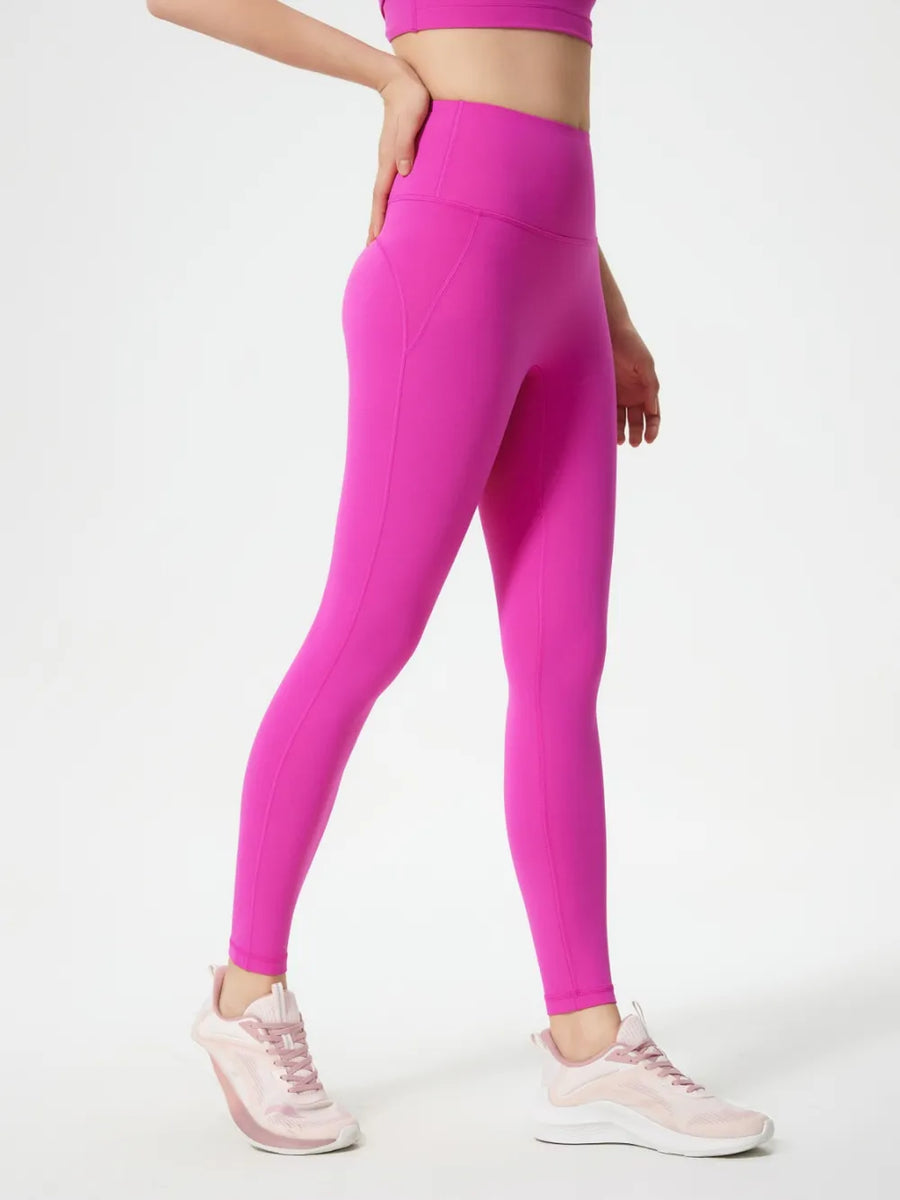 Person wearing bright pink leggings and a matching top on a white background