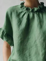 Green blouse with ruffled collar and sleeves on a plain background
