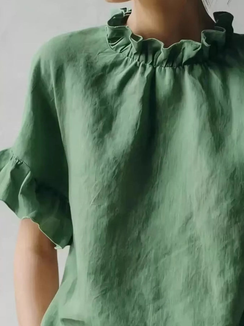 Green blouse with ruffled collar and sleeves on a plain background