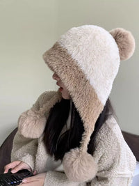 Person wearing a fluffy hooded coat with bear ears, sitting indoors.
