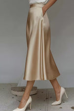 Gold satin skirt worn by a person on a neutral background