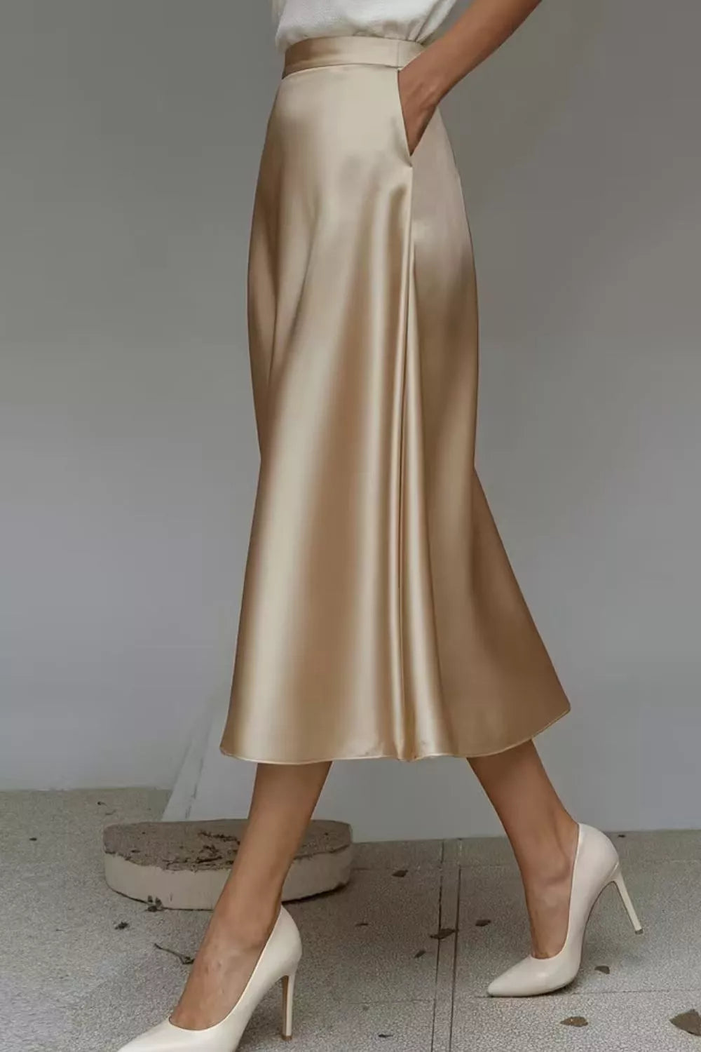 Gold satin skirt worn by a person on a neutral background