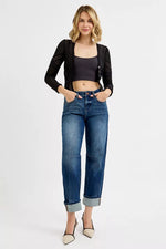 Woman wearing a black jacket, black top, and blue jeans on a white background