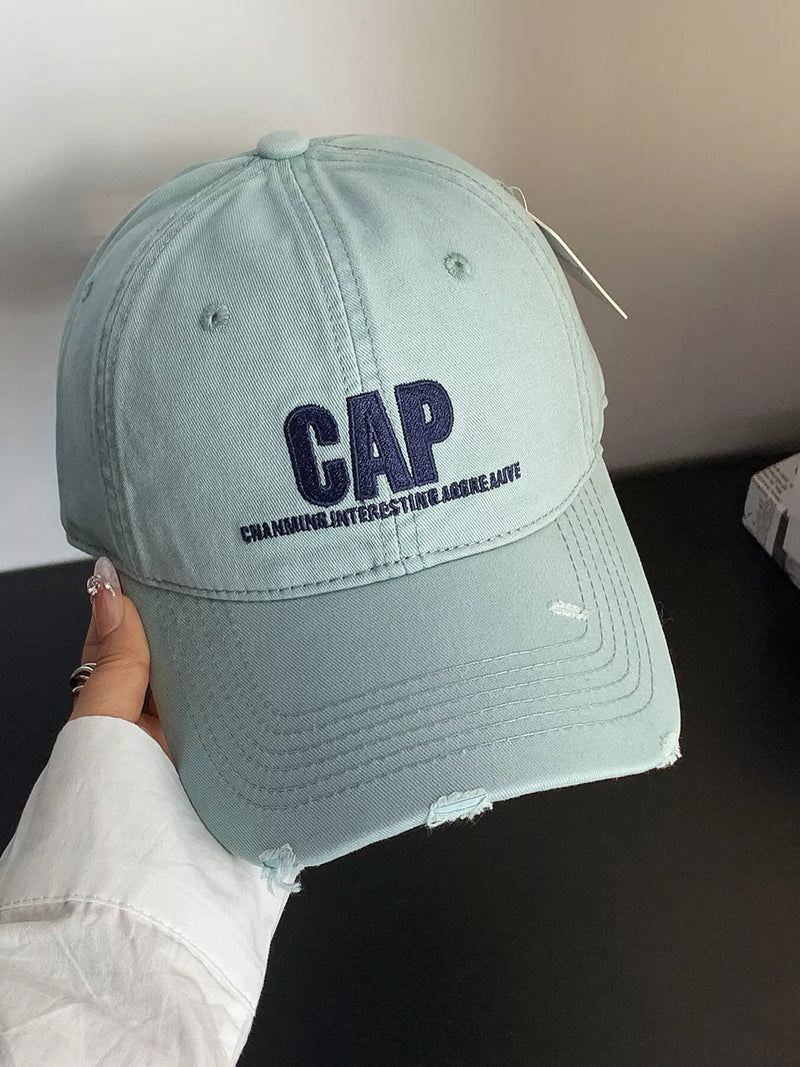 Light blue cap with 'CAP' and text held by a person against a neutral background
