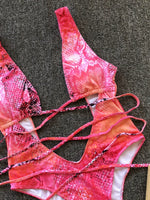 Pink and orange patterned bikini set on a textured surface