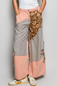 Person wearing a patchwork skirt with floral and striped patterns on a plain background