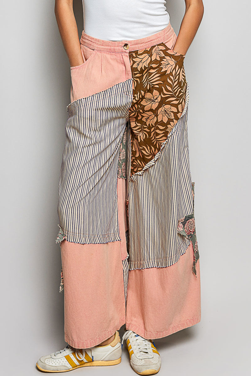 Person wearing a patchwork skirt with floral and striped patterns on a plain background