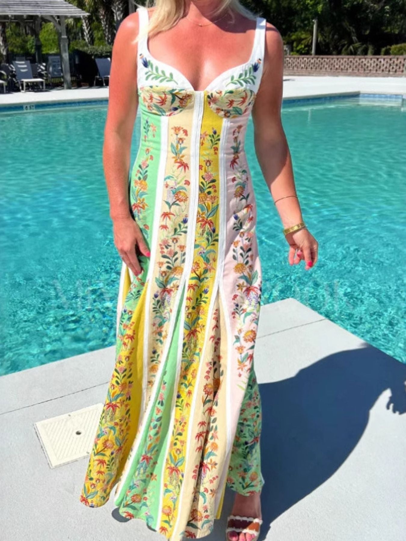 Woman in a colorful dress standing by a pool
