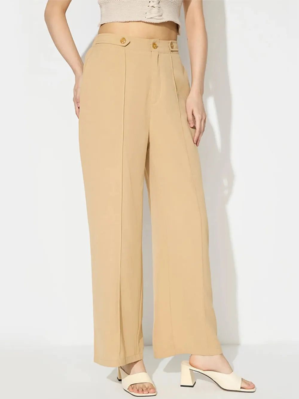 Beige pants worn by a person on a white background