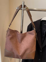 Brown leather handbag hanging on a rack with a beige wall background
