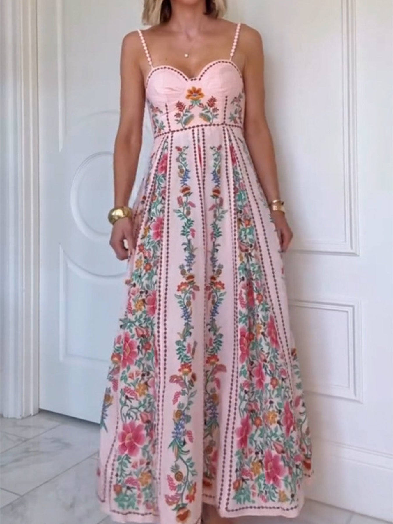 Woman wearing a pink floral dress against a white door.