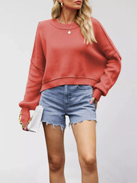 Person wearing a red sweater and denim shorts on a plain background