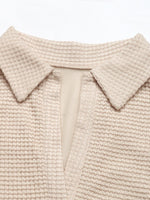 Close-up of a beige knitted garment with a collar on a white background
