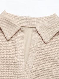Close-up of a beige knitted garment with a collar on a white background