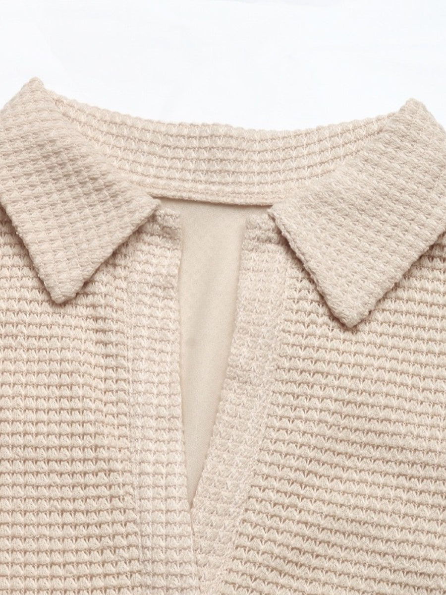 Close-up of a beige knitted garment with a collar on a white background
