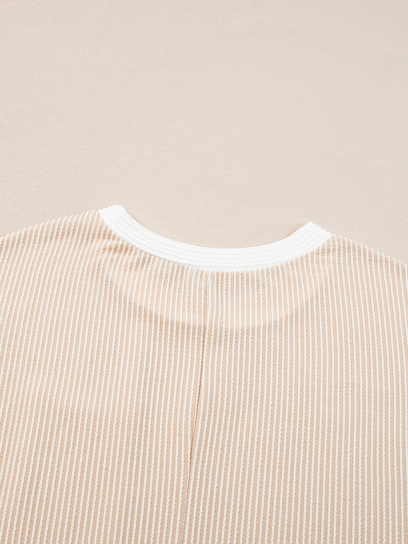 Close-up of a beige and white striped shirt collar on a beige background