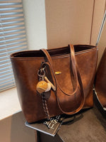 Brown leather tote bag with a keychain on a surface