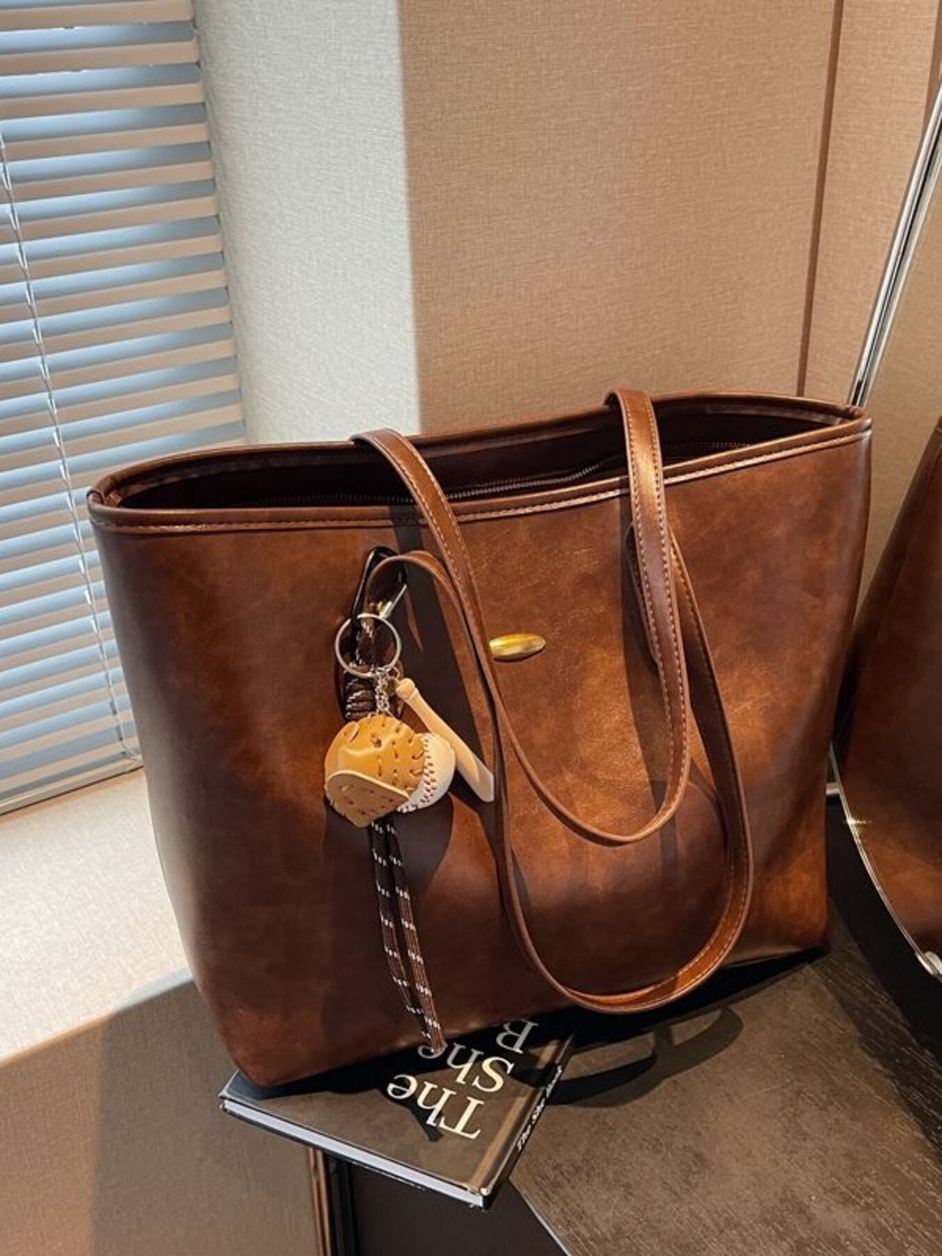 Brown leather tote bag with a keychain on a surface