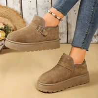 Brown suede shoes with buckles worn by a person, on a beige background