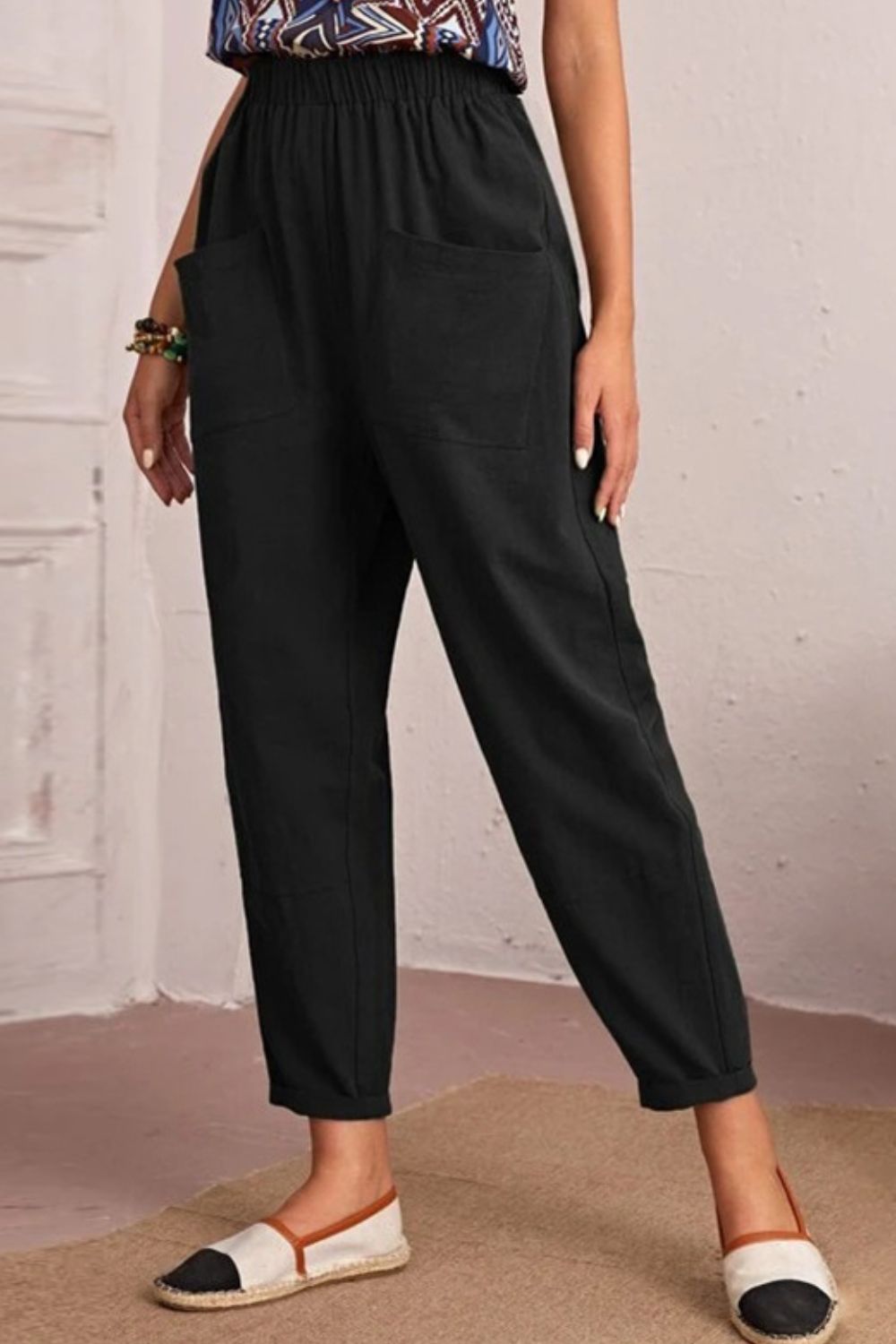 Person wearing black pants with a plain background