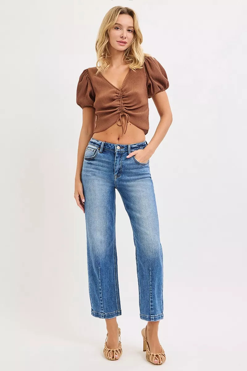 Woman wearing a brown top and blue jeans on a white background