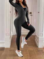 Person wearing a black athletic outfit with white sneakers in a room.