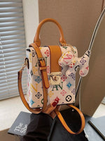 Designer handbag with colorful pattern and brown leather accents on a neutral background