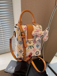 Designer handbag with colorful pattern and brown leather accents on a neutral background