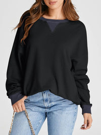 Person wearing a black sweater and blue jeans on a white background