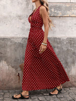 Woman wearing a red polka dot dress against a textured wall.