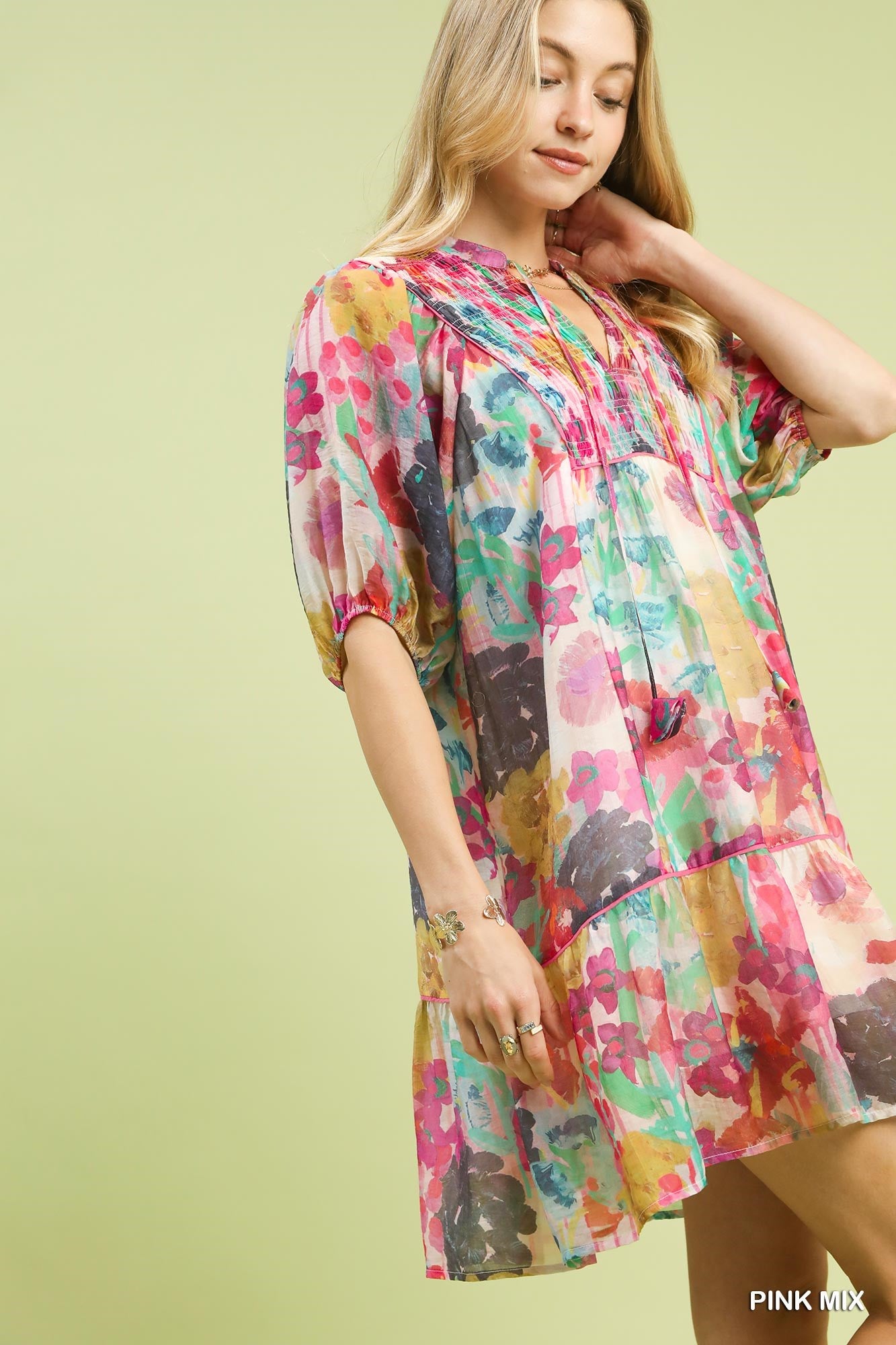 Woman wearing a colorful floral dress against a light green background