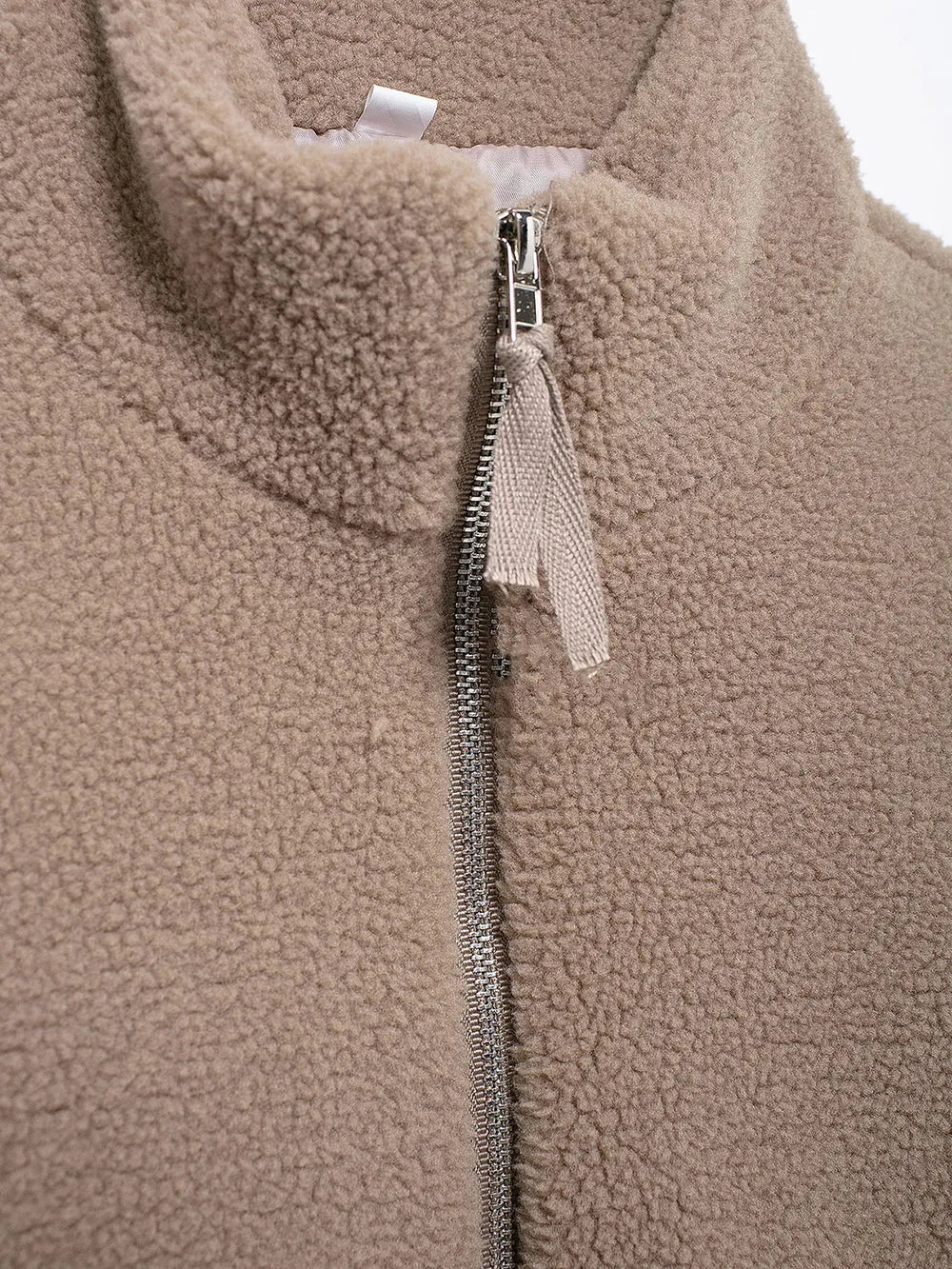 Close-up of a brown fleece jacket with a zipper and tag.